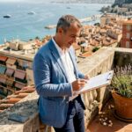 Agent reviews listings on balcony above French Riviera
