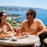 Happy couple enjoying drinks on sunny beach terrace