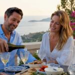 Couple pouring wine on sunny Riviera terrace